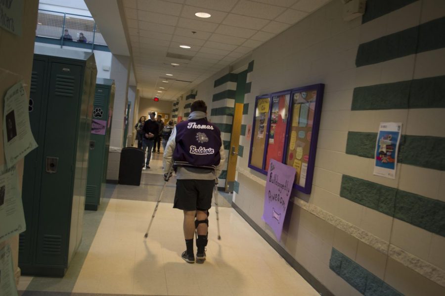 Sophomore Toby Thomas pictured wearing his letterman jacket while on crutches.  Thomas had previously injured himself during his wrestling season tearing his meniscus.