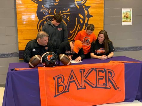 Senior Alex Berg signs to become a Baker Wildcat next year, suiting up for the football team. Seated next to Berg are his parents, both also BU alumni.